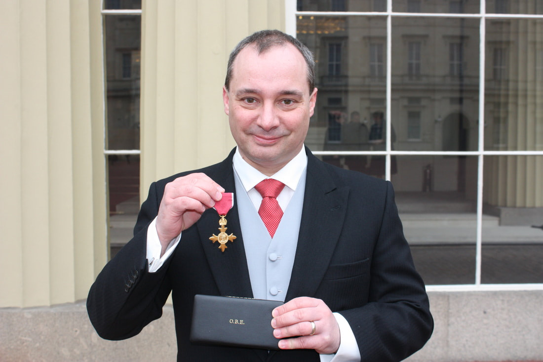 Prof Richard Wilding holding his OBE medal